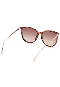 Gafas de sol de carey con forma de ojo de gato, lentes degradados, acentos metálicos y finas patillas doradas. Superficie lisa y montura redondeada.