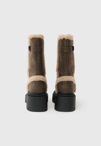 Barna velúr bokacsizma bézs műszőrme béléssel, fekete platform talppal és oldalán állítható pánttal.