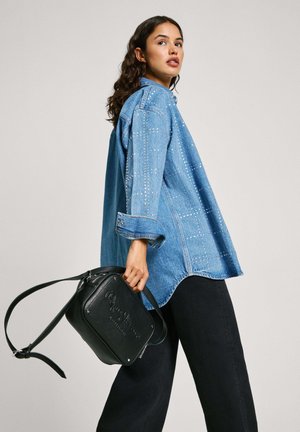 Denim särg koos narmastega, mugav lõige, helesinine värv, nööpidega mansetid. Must nahkne õlakott, millel on hõbedane brändi trükk.