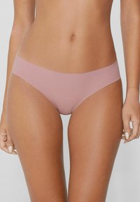 Světle růžové hladké bikiny, které mají nízký střih a minimalistické elastické pásky v pase a na nohavicích.