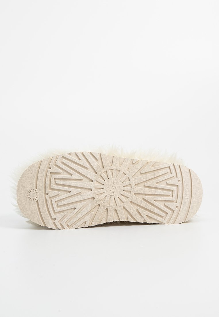 Suola di una ciabatta morbida di colore crema con fondo in gomma testurizzata caratterizzato da un motivo a raggiera per migliorare la presa e la trazione.