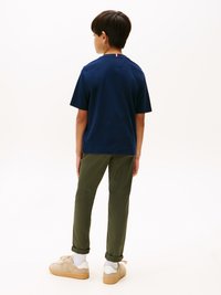 Tricou din bumbac navy cu mâneci scurte, asociat cu pantaloni verzi măslinii și adidași bej. Design simplu, fără modele sau grafice vizibile.