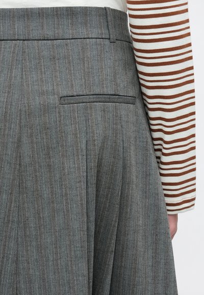 Γκρι πλισέ φούστα με διακριτικό σχέδιο ψαροκόκκαλο, με τσέπη στο πίσω μέρος και μαλακή υφή. Συνοδεύεται από ριγέ μπλούζα μακρυμάνικη.