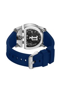 Srebrn zapestni ura s pregibnim hrbtom, prozornim črnim brezom, vidnimi zobniki in modrim silikonskim trakom z vgrajenim kovinskim sponko, na katerem je vgravirana beseda "POLICE".