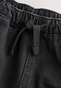 Close-up of black elastic waistband with drawstring tied in a bow on soft fabric pants.