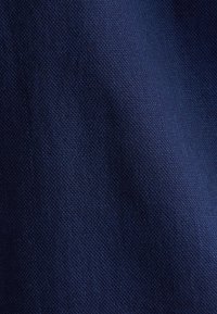 Tessuto tricotato blu navy con una densa trama, che presenta una superficie liscia e una leggera lucentezza. Nessun motivo o hardware visibile.