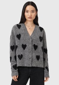 Cardigan grigio realizzato in materiale morbido, con motivi a cuore neri. Presenta un collo a V, maniche lunghe e cinque bottoni sul davanti.