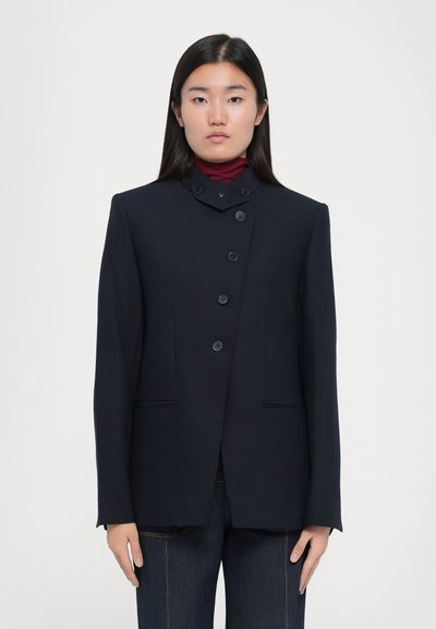 Marineblauer Blazer mit hohem Kragen, fünf Knöpfen vorne und zwei Fronttaschen. Glatte Stofftextur und strukturierte Silhouette.