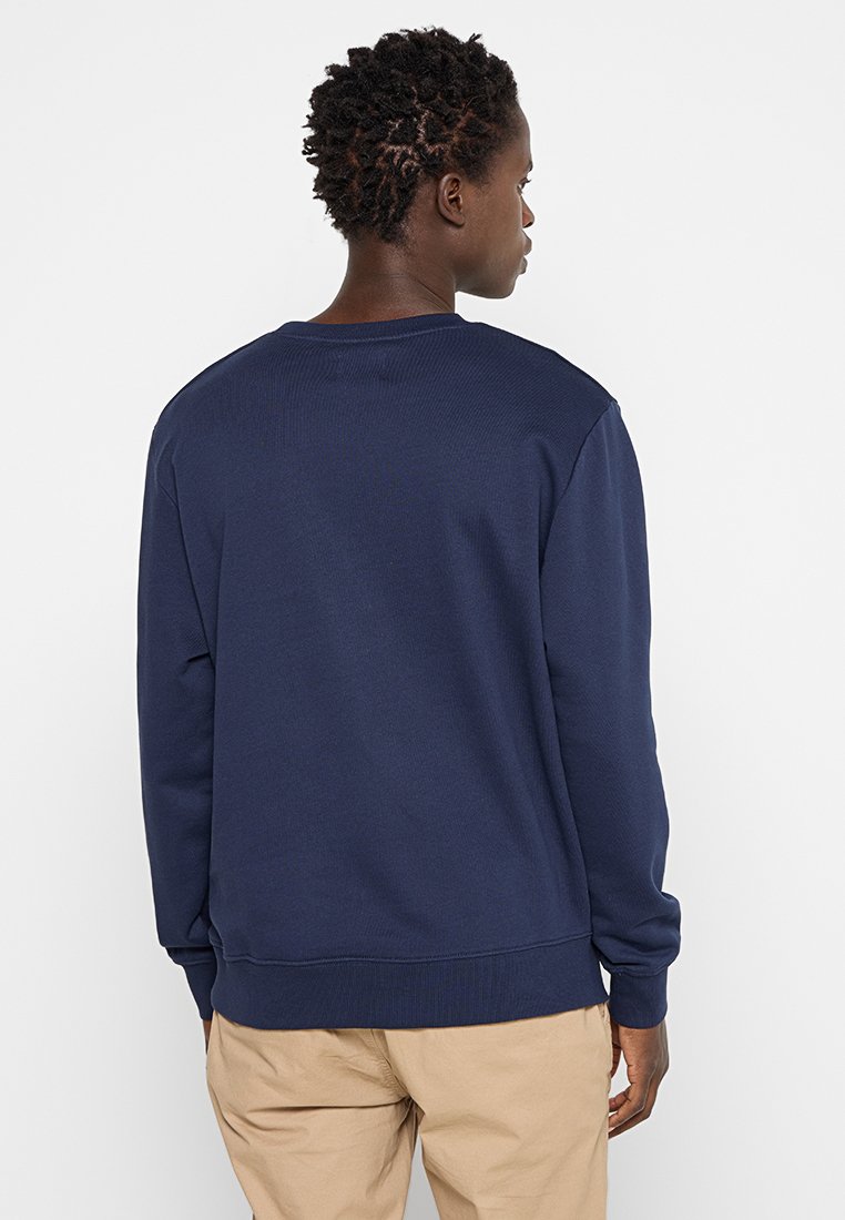 Granatowy sweatshirt z okrągłym dekoltem, z prążkowanymi mankietami i dołem. Wykonany z miękkiego materiału, o prostym wzornictwie i czystych liniach.