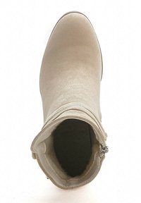Botín beige con parte superior de tela suave, diseño curvado y tacón bajo. Cuenta con un cierre de cremallera en el lateral y un forro interior texturizado.