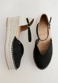 Pantofi wedge negri din suede cu partea superioară țesută albă, branț din plută și talpă din iută împletită. Include curea pentru gleznă și cusături decorative.