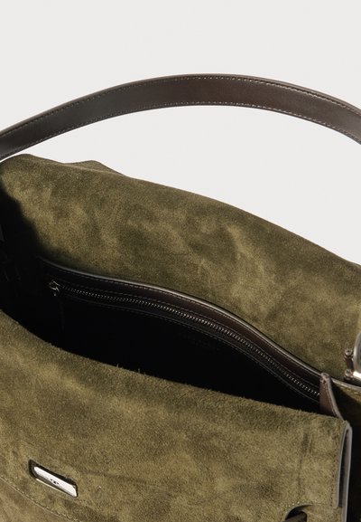 Μαλακή τσάντα χρώματος ελιάς από σουέτ με σκούρο καφέ δερμάτινη λαβή και τσέπη με φερμουάρ στο εσωτερικό, με λείο υφασμάτινο υλικό και μινιμαλιστικό σχέδιο.