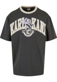 Dark gray oversized t-shirt with short sleeves, beige ribbed collar, and prominent white printed logo featuring an eagle and established date.