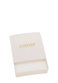 Pequeña caja de joyería blanca con texto dorado "amor" en la tapa, parcialmente abierta mostrando su interior vacío.