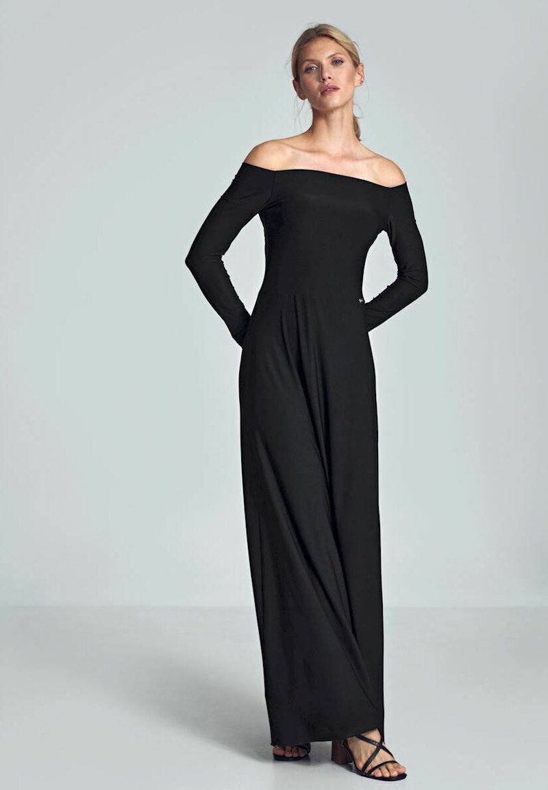 Zwarte off-shoulder jumpsuit van rekbare stof, met lange mouwen en een vloeiende silhouet, gecombineerd met zwarte strappy sandalen.