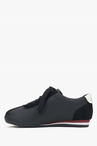 Czarne sneakersy o gładkiej syntetycznej powierzchni, z teksturowanymi akcentami z zamszu, płaskimi sznurowadłami i białą pętelką pięty z logo, w czerwono-białą paskowaną podeszwą.