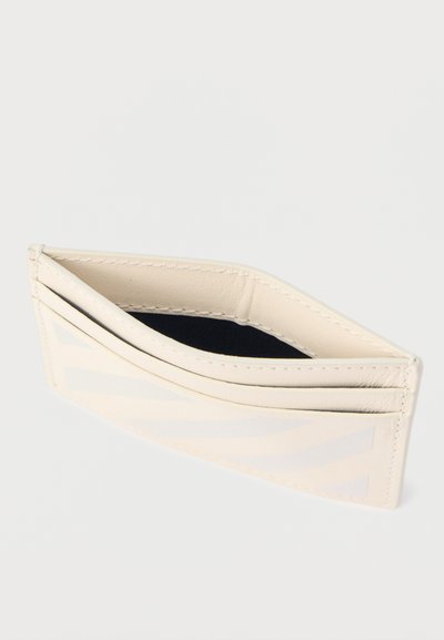 Λεπτό δερμάτινο πορτοφόλι κάρτας σε κρεμ απόχρωση με πολλαπλές θήκες και κεντρικό διαμέρισμα σε φωτεινό φόντο.