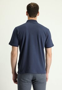 Polo shirt blu navy realizzato in tessuto morbido, caratterizzato da un colletto classico e maniche corte, con orlo dritto e dettagli minimi.