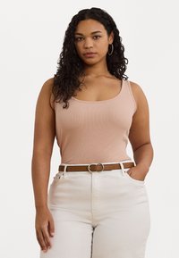 Ljusrosa ribbad linne med rundad halsringning, kombinerat med högmidjade krämfärgade byxor och ett brunt bälte med en silverfärgad spänne.