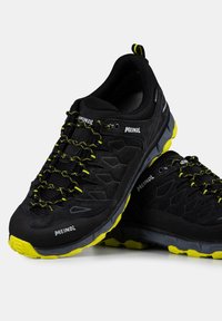 Czarne buty sportowe z teksturowaną cholewką z zamszu, żółtymi akcentami i wzorzystą podeszwą. Posiadają system szybkiego sznurowania oraz wzmocniony zapiętek.