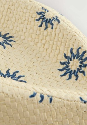 Panier tissé avec une texture couleur crème, arborant des motifs floraux brodés en bleu et un bord lisse et arrondi.