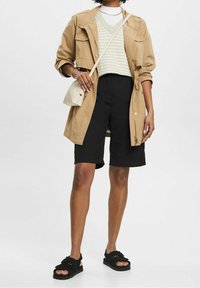 Veste légère beige, pull rayé blanc et menthe, short noir et sandales noires. Comprend un petit sac bandoulière crème.