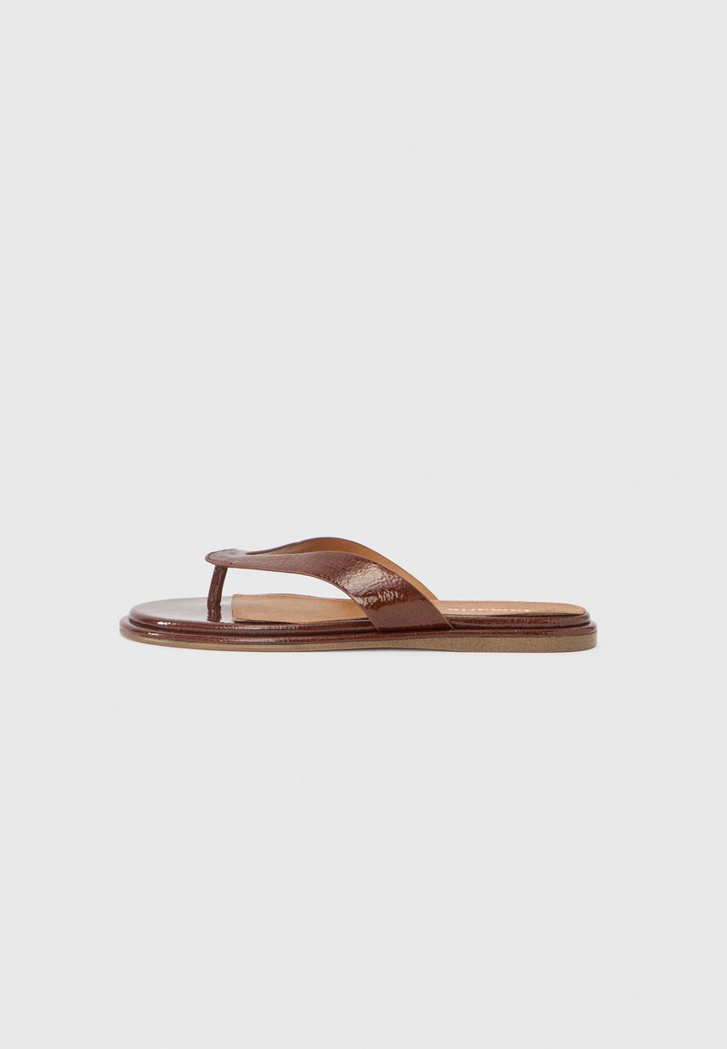 Tongs en cuir marron avec une bride texturée et une semelle intérieure lisse. Présente un design minimaliste et une semelle plate, adaptées pour un usage décontracté.