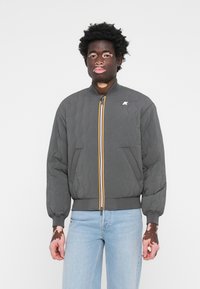 Καπιτονέ γκρι τζάκετ μπομπέρ με κίτρινο και μπλε φερμουάρ, ραβδωτές μανσέτες και τελείωμα, διαθέτει πλάγιες τσέπες και λογότυπο στην τσέπη του στήθους.