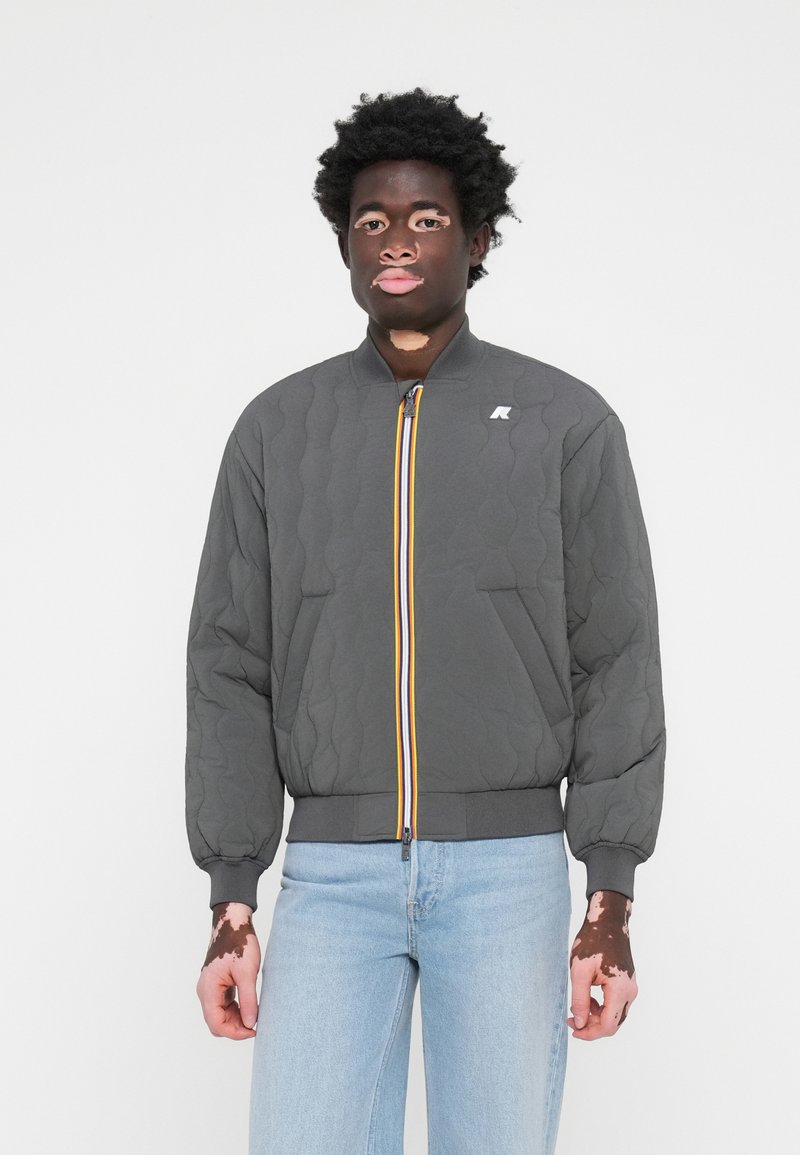 Καπιτονέ γκρι τζάκετ μπομπέρ με κίτρινο και μπλε φερμουάρ, ραβδωτές μανσέτες και τελείωμα, διαθέτει πλάγιες τσέπες και λογότυπο στην τσέπη του στήθους.