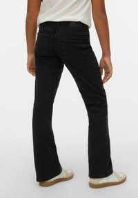 Svarta utsvängda jeans med en mjuk textur och klassisk design. Har bakfickor och en kontrasterande midjeresår med subtil logotypdetalj.