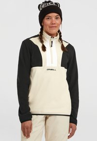 Fleece pullover in beige en zwart, met een rits hals, contrasterende panelen en het "O'Neill" logo op de voorkant. Gekleed met een gebreide beanie.