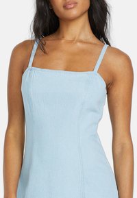 Helles blaues Denim-Kleid mit quadratischem Ausschnitt, dünnen Trägern und Nähten, das eine glatte Textur und eine taillierte Silhouette aufweist.