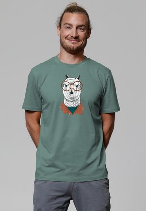 Mintgroene katoenen T-shirt met een grafisch ontwerp van een lama met een bril, die een bruine halsband draagt, tegen een effen grijze achtergrond.