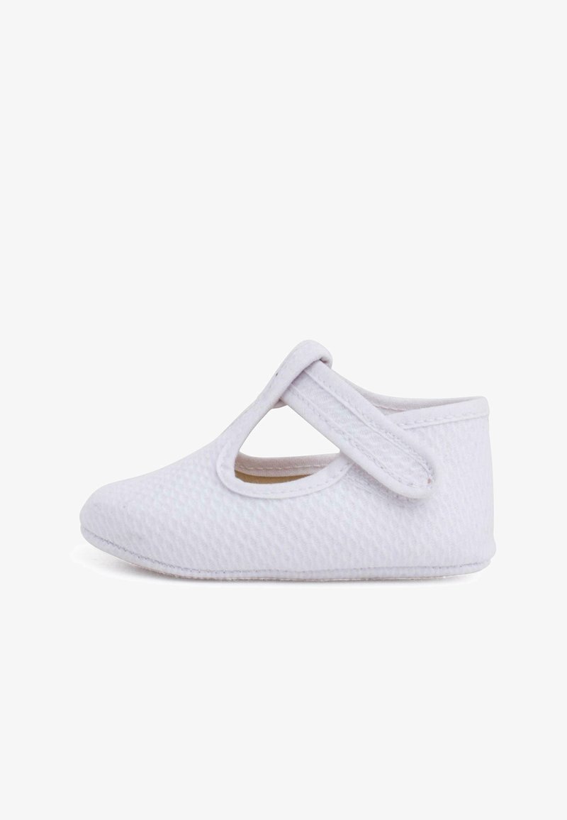 Chaussure souple blanche avec un motif texturé, maintenue par une sangle sur le dessus, présentant un design découpé sur les côtés. Légère et flexible.