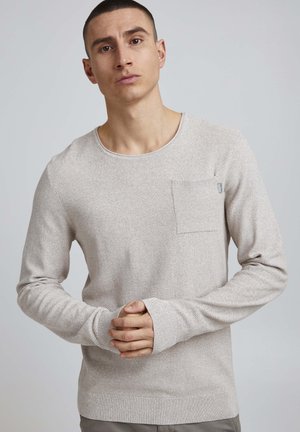 Chemise à manches longues gris clair texturé avec un col rond et une poche poitrine. Matière tricot douce avec des poignets et un ourlet côtelés.