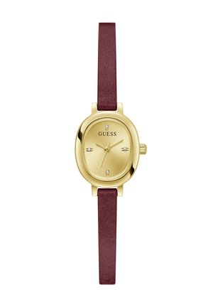 Cadran de montre ovale doré avec quatre petits cristaux et logo "GUESS", associé à un bracelet en cuir fin rouge foncé.