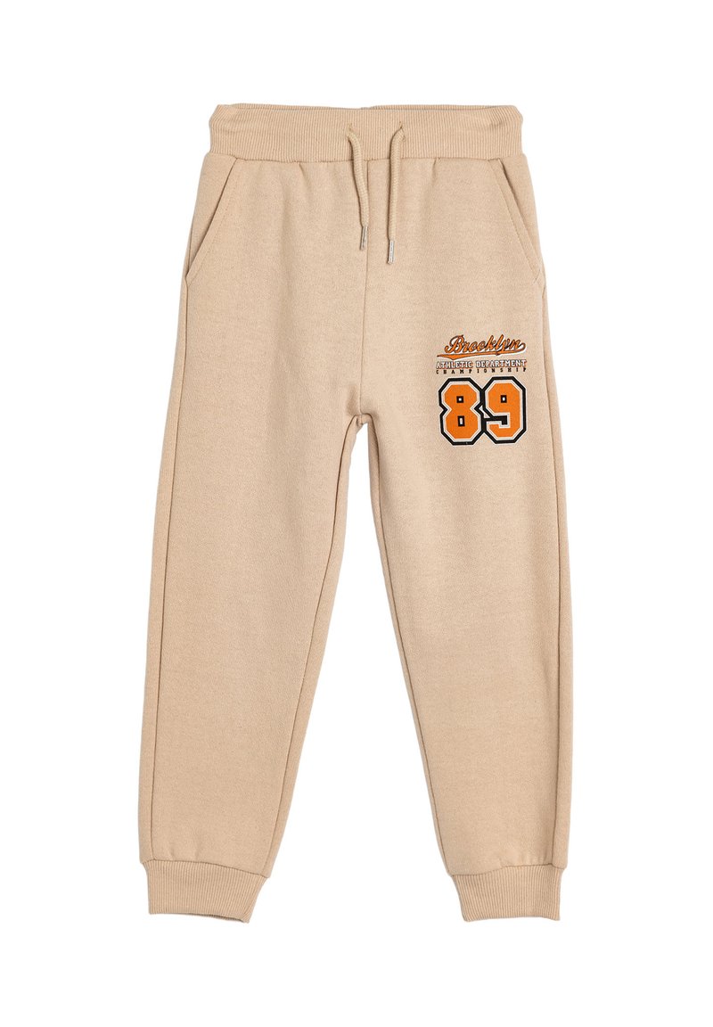 Pantalones de chándal beige hechos de un tejido suave, con cinturilla elástica, bolsillos laterales y un diseño impreso con "Brooklyn" y el número "89".