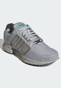 Szare buty sportowe z siateczkowymi wstawkami, teksturowanym wykończeniem i grubą podeszwą. Posiadają turkusowe logo oraz regulowany pasek na sznurowadłach.
