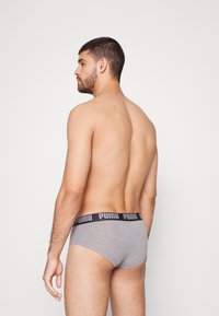 Graue Baumwollslips mit einem schwarzen elastischen Bund, der das "PUMA"-Logo trägt. Das Design ist schmal geschnitten und betont die Körperform von hinten.