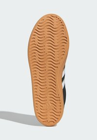 Crni potplat tenisice s uzorkom valova i svijetlo smešnim gumenim materijalom. Ima bijele pruge i urezani logo.