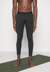 Leggings deportivos negros hechos de material elástico con una ancha cinturilla elástica y un sutil detalle de logo en el muslo.