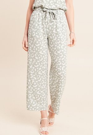 Pantalon vert à jambes larges avec des taches abstraites blanches, ceinture nouée à la taille, associé à un haut assorti et des sandales blanches à bout ouvert avec un motif cœur.