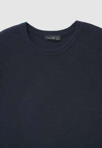 Maglione blu navy in tessuto testurizzato con scollo a girocollo e polsini a coste. Presenta un'etichetta "CALLIOPE" e una targhetta con taglia L. Tessuto morbido con un motivo sottile.