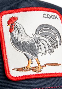 Casquette de baseball avec un patch blanc présentant un coq gris brodé avec une crête rouge et des pattes orange, encadré d'une couture rouge.