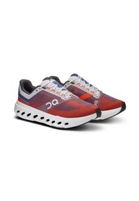 Red and gray running shoes with a lightweight mesh upper, white midsole, and circular cutouts; features contrasting blue and orange accents.