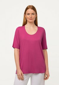 Top fucsia a maniche corte con scollatura a scoop, realizzato in tessuto morbido. Presenta una vestibilità comoda e spacchi laterali per un tocco di stile in più.
