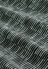 Black and white fabric with wavy horizontal stripes and small vertical dashes, shown in close-up folds.