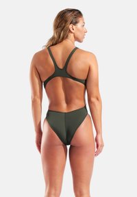 Oliivinvihreä uimapuku, jossa on korkealle leikattu alaosa ja racerback-muotoilu. Sileä pinta, minimaaliset koristeet ja avoin selkä.
