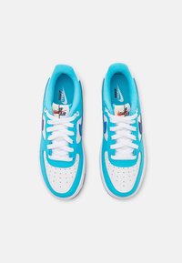 Paire de baskets Nike Air bleues et blanches avec des lacets blancs, vues de dessus sur un fond uni clair.
