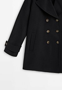 Manteau en mélange de laine noire avec un design à double boutonnage, de grands revers, et des boutons dorés. Comprend une poche latérale et des manches avec revers.